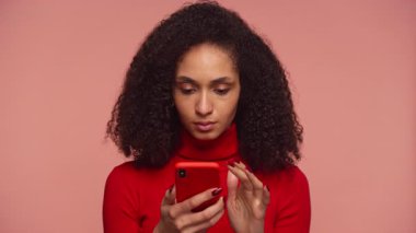 Sinirli bir kadın, telefonuna güvensizlik ve hayal kırıklığıyla bakıyor. Mesaj ya da konu yüzünden kafası karışık.