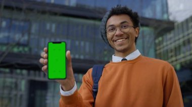 Şehirde yeşil ekran modeli olan mutlu öğrenci telefonu, uygulama veya UI önizlemesi için şehir ortamında harika