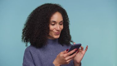 İnternetten alışveriş yaparken elinde akıllı telefon tutan, büyük anlaşmalara ya da stüdyodaki heyecan verici alımlara tepki veren şaşkın ve mutlu genç bir kadın..