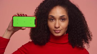 Kırmızılı bir kadının portresi yatay konumdaki akıllı telefonu yeşil ekran ile tutuyor, tasarım ve model kullanımı için ideal..