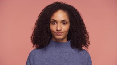 Mavi kazaklı genç bir kadın onaylamayan bir bakışla başını hafifçe sallıyor, anlaşmazlık ya da hafif bir hayal kırıklığı gösteriyor..