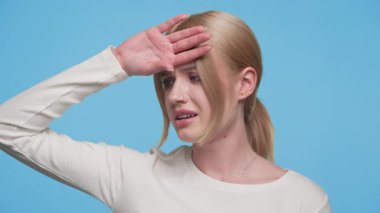 Genç sarışın kadın hasta ve sıkıntılı görünüyor, elini alnına dayamış, sanki ateşi ya da baş dönmesi varmış gibi..