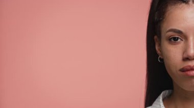 Minimalist görüntü, bir kadının yüzünün sağ yarısını pembe bir zemine, güzellik, kimlik ya da duygu temalarına karşı gösteriyor..