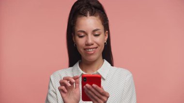 Beyaz benekli tişörtlü genç kadın telefonunda şok edici ya da üzücü haberler okurken şaşkın ve sıkıntılı görünüyor..