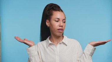 Beyaz benekli tişörtlü genç bir kadın iki elini de uzatıyor. Mavi arka plandaki belirsizliği ifade eden seçenekleri tartıyormuş gibi..