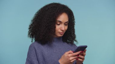 Genç kadın, akıllı telefonundan rahatsız edici bir şey okurken hayal kırıklığına uğramış ve hoşnutsuz görünüyor. Stüdyo ortamında hayal kırıklığını gösteriyor..