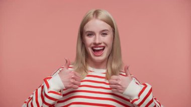 Çizgili tişörtlü, gülümseyen sarışın kadın olumlu ve pembe arka plana karşı onay veriyor..