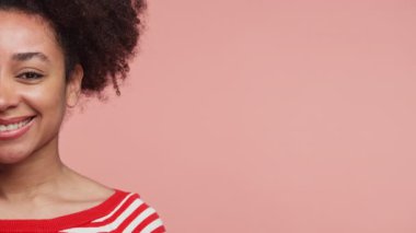 Kırmızı ve beyaz çizgili gömlek giyen gülümseyen bir kadının kesilmiş portresi, boş kopya alanı olan pembe bir arka plan üzerine kurulmuş..