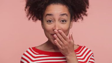 Kırmızı çizgili gömlekli neşeli genç bir kadın, pembe arka planda izole edilmiş, ağzını olumlu bir şokla kaplayarak, neşeli bir sürpriz ve zevkle tepki veriyor..