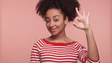 Kırmızı ve beyaz çizgili tişörtlü neşeli bir kadın pembe arka planda elinde 