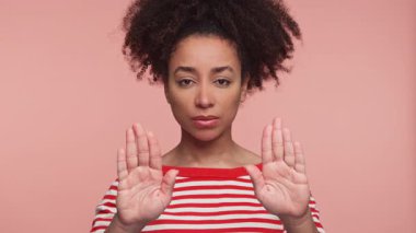 Ciddi bir genç kadının portresi, yumuşak pembe bir arka plana karşı iki elini de havaya kaldırdı..