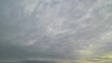 Erken ya da geç saatlerde ufuk yakınında yumuşak doğal ışık ile, dokulu bir gökyüzünde hızlı hareket eden bulutların zamanaşımı görüntüsü.