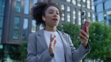 Akıllı telefon ve kulaklıklarla modern kentsel iş bölgesinde işe gidip gelen kendine güvenen genç profesyonel kadın videosu..