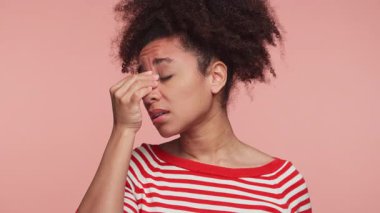 Hüsrana uğramış genç bir kadının burun köprüsünü gözleri kapalı tutması sinüs ağrısı ve baş ağrısından kaynaklanan rahatsızlık ve gerilimi gösteriyor..