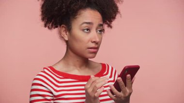 Çizgili tişörtlü endişeli genç bir kadın. Hayal kırıklığına uğramış bir ifadeyle telefona bakıyor. İnternette olumsuz bir şeye tepki veriyor..