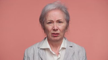Resmi ceketli yaşlı kadın üzgün ve endişeli görünüyor, kötü ya da hayal kırıklığı yaratan haberlere tepki veriyor..