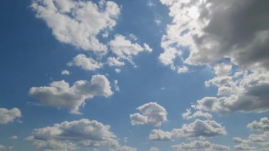 Yumuşak beyaz bulutlarla dolu parlak mavi bir gökyüzünün manzarası sakin ve huzurlu bir doğal atmosfer yaratıyor..