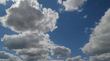 Derin mavi gökyüzünde sürüklenen kabarık bulutların dinamik hızlandırılmış görüntüsü, hareket ve doğal hava modellerini gösteriyor..