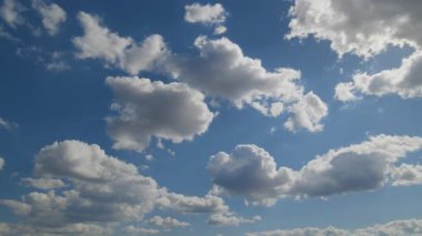 Yumuşak beyaz bulutlar, parlak mavi bir gökyüzünde yavaş yavaş şekillenir ve çözülür, barışçıl bir atmosferik hızlandırma sekansıyla yakalanır..