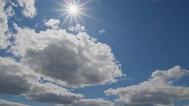 Dinamik gökyüzü, parlak mavi gökyüzünde süzülen tüylü bulutlarla birlikte, ışıldayan güneş tarafından aydınlatılarak yayılıyor..