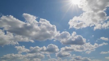 Kümülüs bulutlarının dinamik hızlandırılmış kümülüs bulutları parlak mavi bir gökyüzünde hareket ediyor. Güneş parlıyor, havayı ve doğayı yakalıyor..