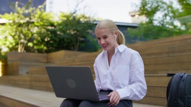 Dışarıda dizüstü bilgisayarıyla oturan genç bir kadın internette gezinirken okuduğu iyi haberlere hoş bir sürpriz yapıyor..