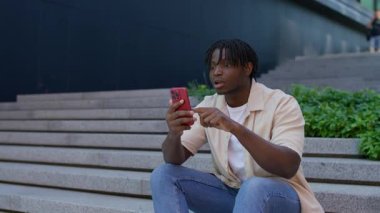 Havalara uçmuş genç bir adam heyecan verici haberler aldıktan sonra kutlama yapıyor ya da akıllı telefondan kişisel bir hedefe ulaşıyor..