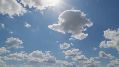 Beyaz kümülüs bulutlarının güneş ışığı altında parlak mavi bir gökyüzünde sürüklenerek barışçıl ve havadar bir atmosfer oluşturduğu güzel bir bulut..