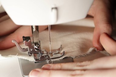 Dikiş işleminin detaylı bir görüntüsü. İplikle iğne yap. Tekstil tutan terzi elleri. Beyaz kumaş dikiyorum. Tekstil endüstrisi.