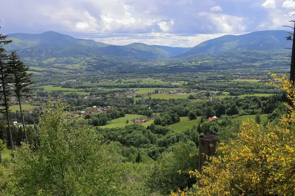 Dağlarda bahar günü. Tarlalar, çayırlar, ormanlar, köy. Bulutlu gökyüzü. Çek Cumhuriyeti 'ndeki Beskydy Dağları Panoraması. Puslu bir arkaplan.
