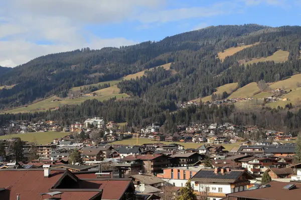 Avusturya, Tirol 'deki Kirchberg: Avusturya' daki Alp kasabası. Baharın başında. Ön plandaki evlerin çatıları, arka plandaki ormanlı dağlar..