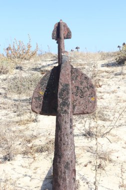 Bu çarpıcı görüntü Portekiz 'in Tavira Adası' ndaki Praia do Barril 'deki ünlü Anchor Mezarlığı' nı gösteriyor. Düzinelerce paslı çapa, kuru bitki örtüsü ve kıyı çalılıklarıyla çevrili kumulların üzerinde sıralanır. Bu tarihi