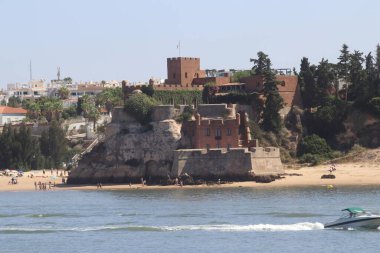 Portekiz 'in Algarve bölgesinde yer alan Ferragudo kıyı köyünün panoramik manzarası. Görüntü, tarihi Sao Joao do Arade Kalesi 'ni vurguluyor. Görkemli bir şekilde korunmuş bir kale.