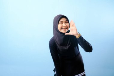 Siyah tesettürlü bir kadın elleriyle jest yapıyor. Bağırarak ya da bir şeyler söyleyerek bir jest yapıyor.