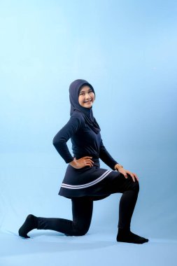 Beyaz çizgili siyah elbiseli bir kadın bir resim için poz veriyor. Siyah bir etek ve siyah pantolon giyiyor.