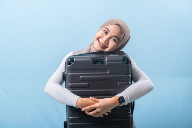 Bir kadın siyah bir bavul tutuyor ve gülümsüyor. Macera ve heyecan kavramı. Kadın bir yolculuğa hazırlanıyor..