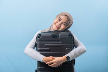 Bir kadın siyah bir bavul tutuyor ve gülümsüyor. Macera ve heyecan kavramı. Kadın bir yolculuğa hazırlanıyor..