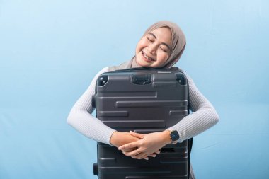 Bir kadın siyah bir bavul tutuyor ve gülümsüyor. Macera ve heyecan kavramı. Kadın bir yolculuğa hazırlanıyor..