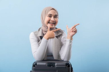 Eşarp takan ve bir şeyi işaret eden bir kadın. Gülümsüyor ve mutlu.