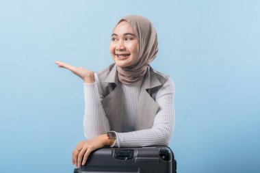 Eşarp takan ve bir şeyi işaret eden bir kadın. Gülümsüyor ve mutlu.