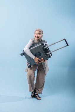 Bir kadın bir bavul tutuyor ve gülümsüyor. Macera ve heyecan kavramı. Kadın bir yolculuğa hazırlanıyor.