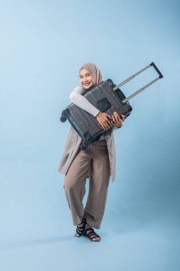 Bir kadın bir bavul tutuyor ve gülümsüyor. Macera ve heyecan kavramı. Kadın bir yolculuğa hazırlanıyor.