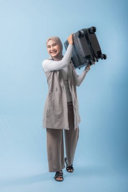 Bir kadın bir bavul tutuyor ve gülümsüyor. Macera ve heyecan kavramı. Kadın bir yolculuğa hazırlanıyor.