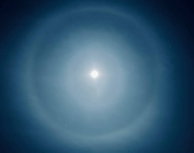 Moon Circles like halos around the full moon over Onchan on the Isle of Man a product of refraction of moonlight through ice crystals clouds in the night sky and often a forecasting bad weather clipart