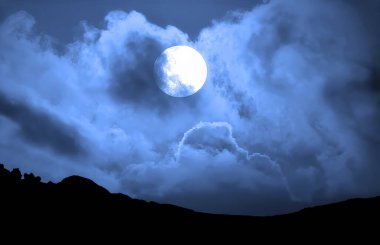 The Full Moon passes behind whispy clouds creating a beautiful but spooky scene clipart