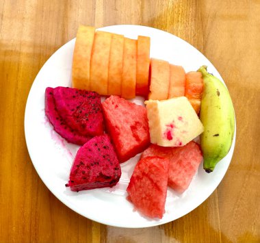 Ejderha meyvesi, karpuz, muz, papaya ve ananas da dahil olmak üzere bir tabak olgun sulu ve lezzetli tropikal meyve.