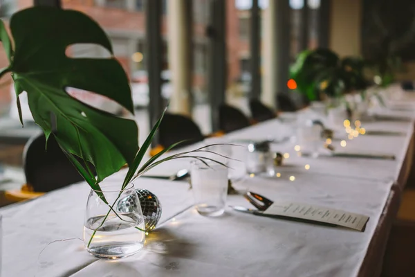 Table setup in a indoor restaurant with dish flowers and lights