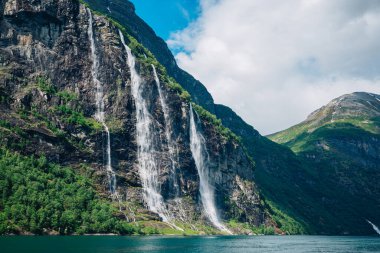 Muhteşem Şelaleler Güneşli bir günde Sersemletici Norveç fiyortlarında Rocky Kayalıklarından aşağı dökülüyor.