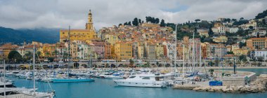 Şatafatlı yatlar ve yelkenli teknelerle dolu canlı bir limana bakan Renkli Binalarla Büyüleyici Sahil Kasabası