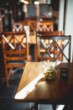 Ahşap Masalar ve Sandalyelerle Samimi Günışığı Kafe İçi Dekoratif Masa Üstü Düzenlemesi